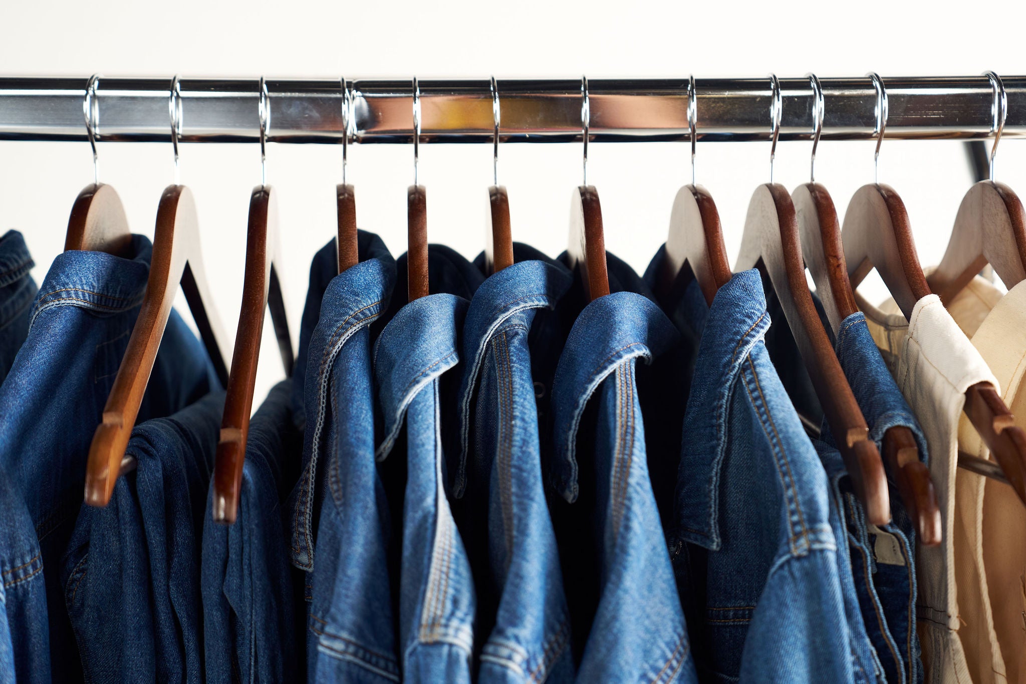Row of denim jackets on hangers against a white background