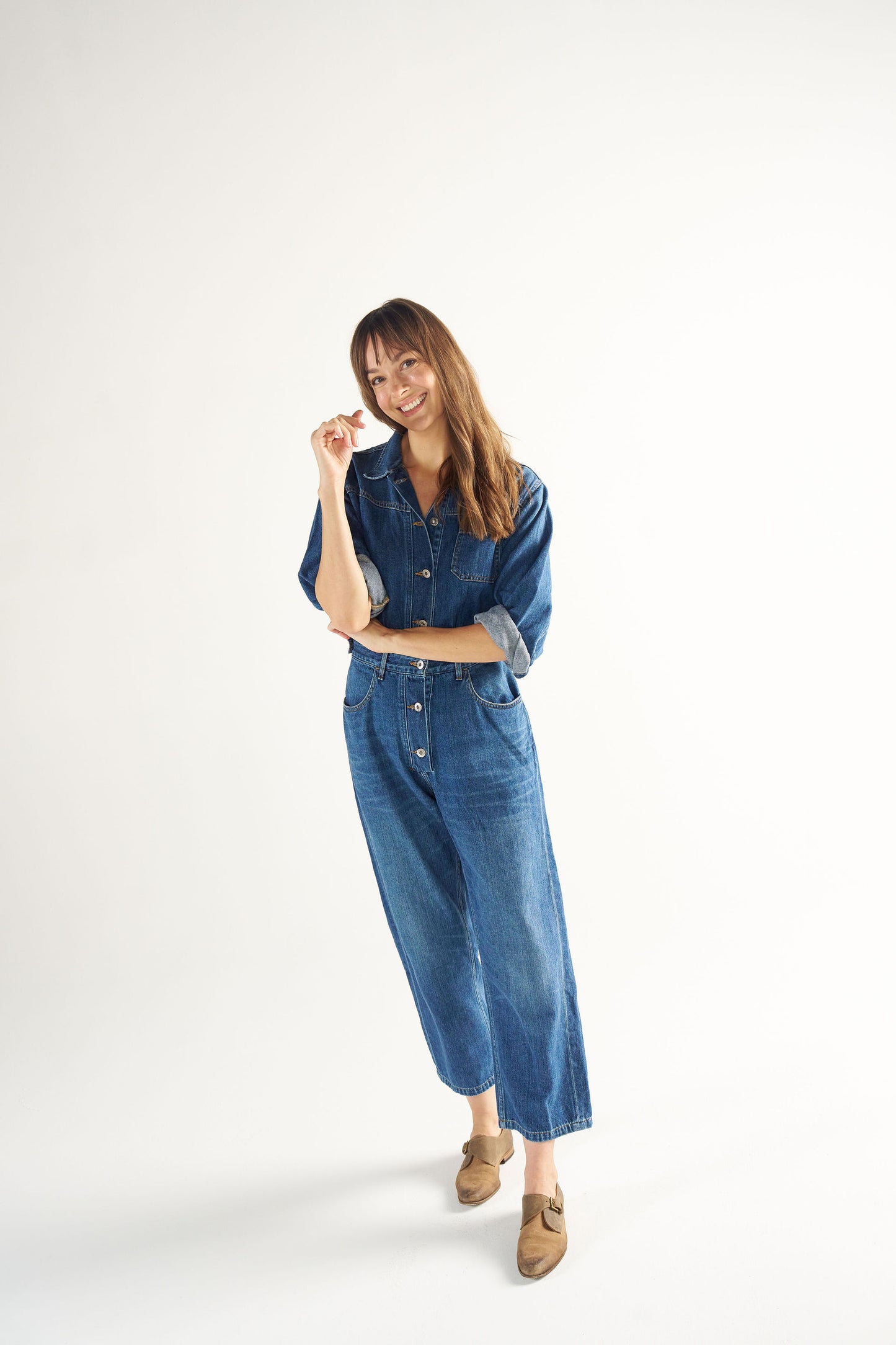 Woman wearing a blue denim jumpsuit on a white background