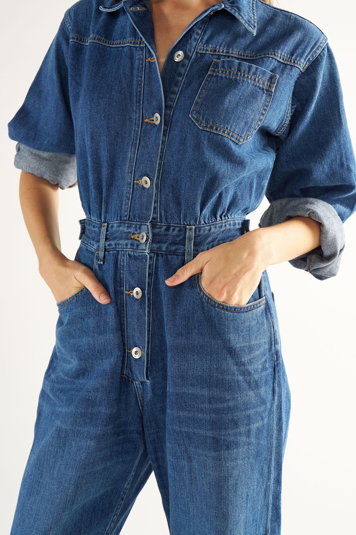 Woman wearing a blue denim jumpsuit on a white background