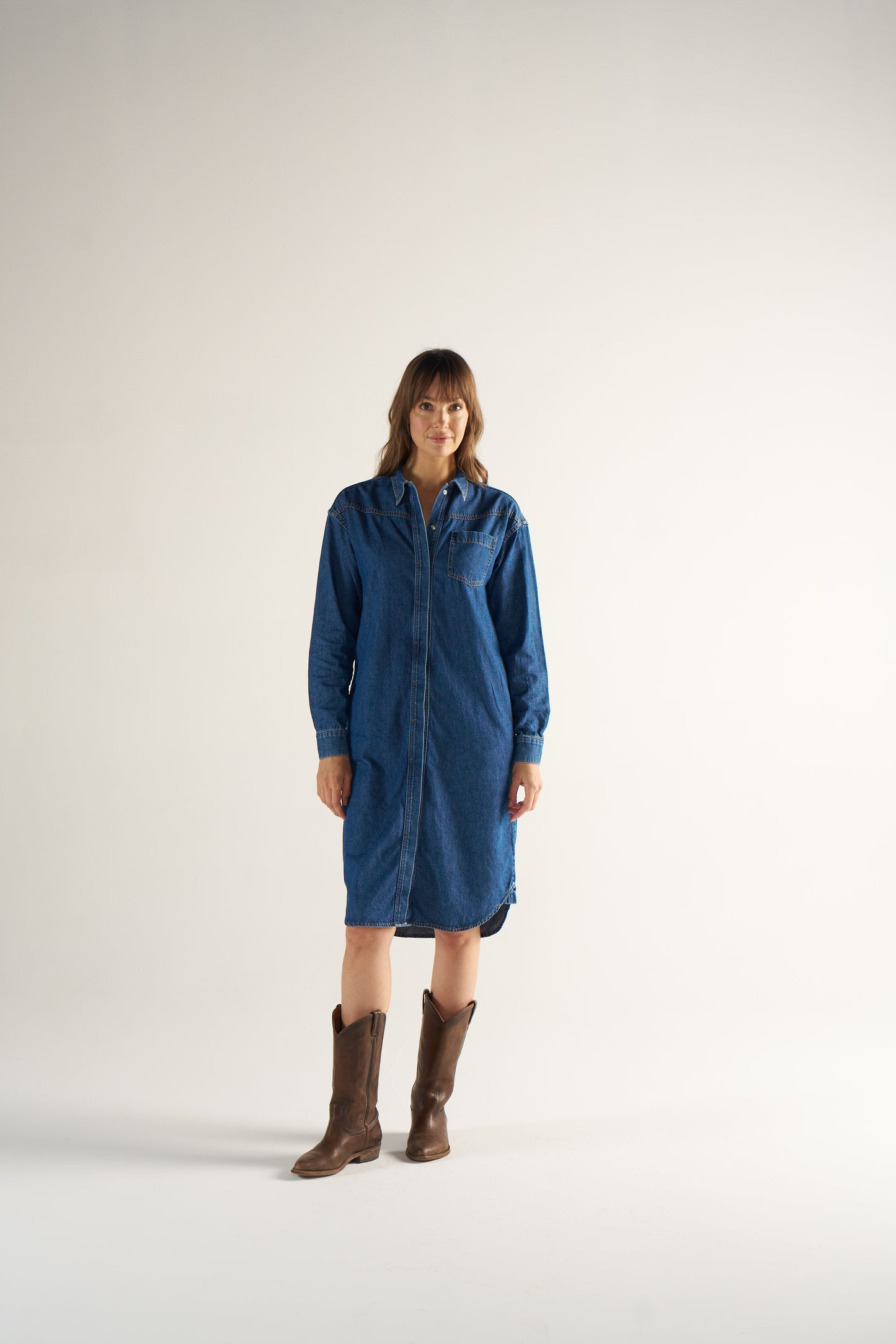Woman wearing a blue dress and brown boots on a white background