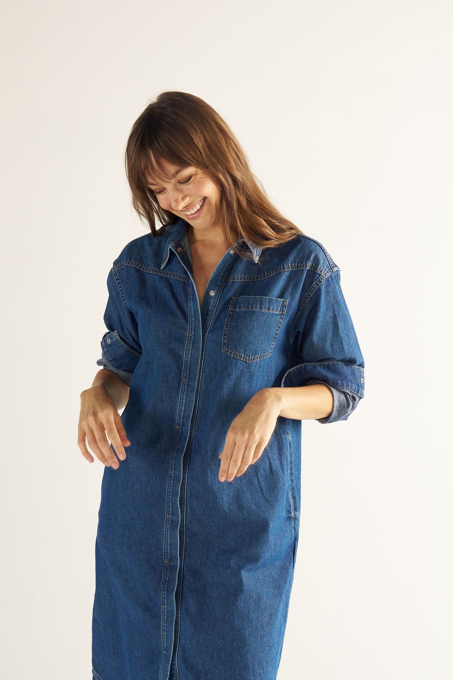 Woman wearing a blue denim dress against a white background