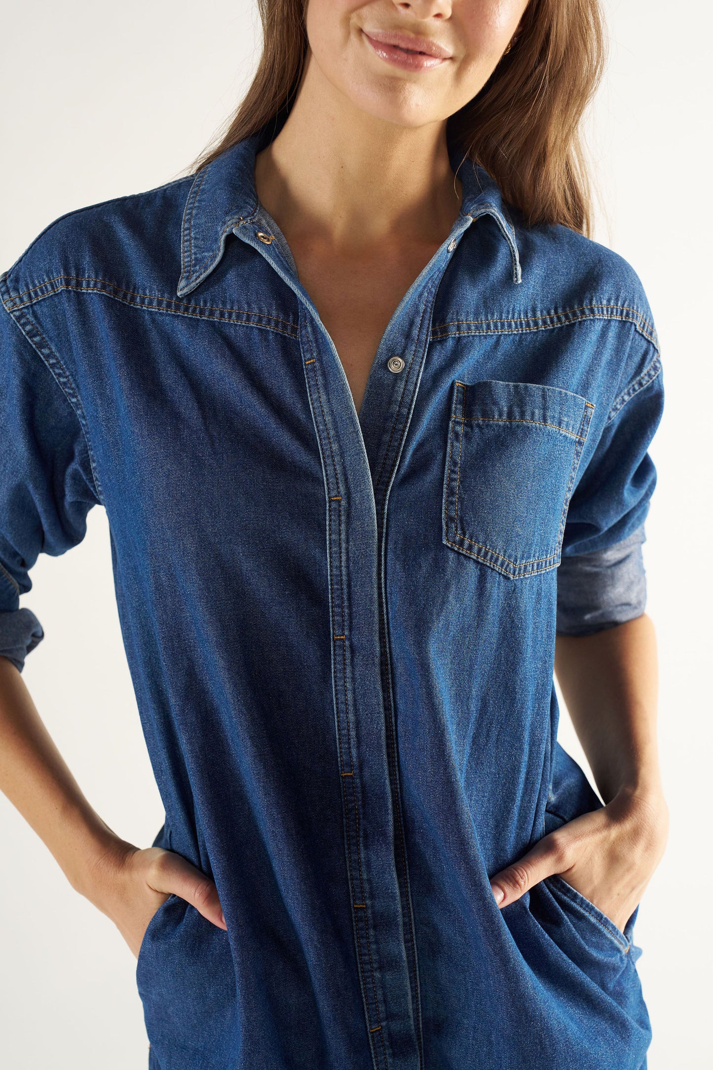 Woman wearing a blue denim shirt against a white background