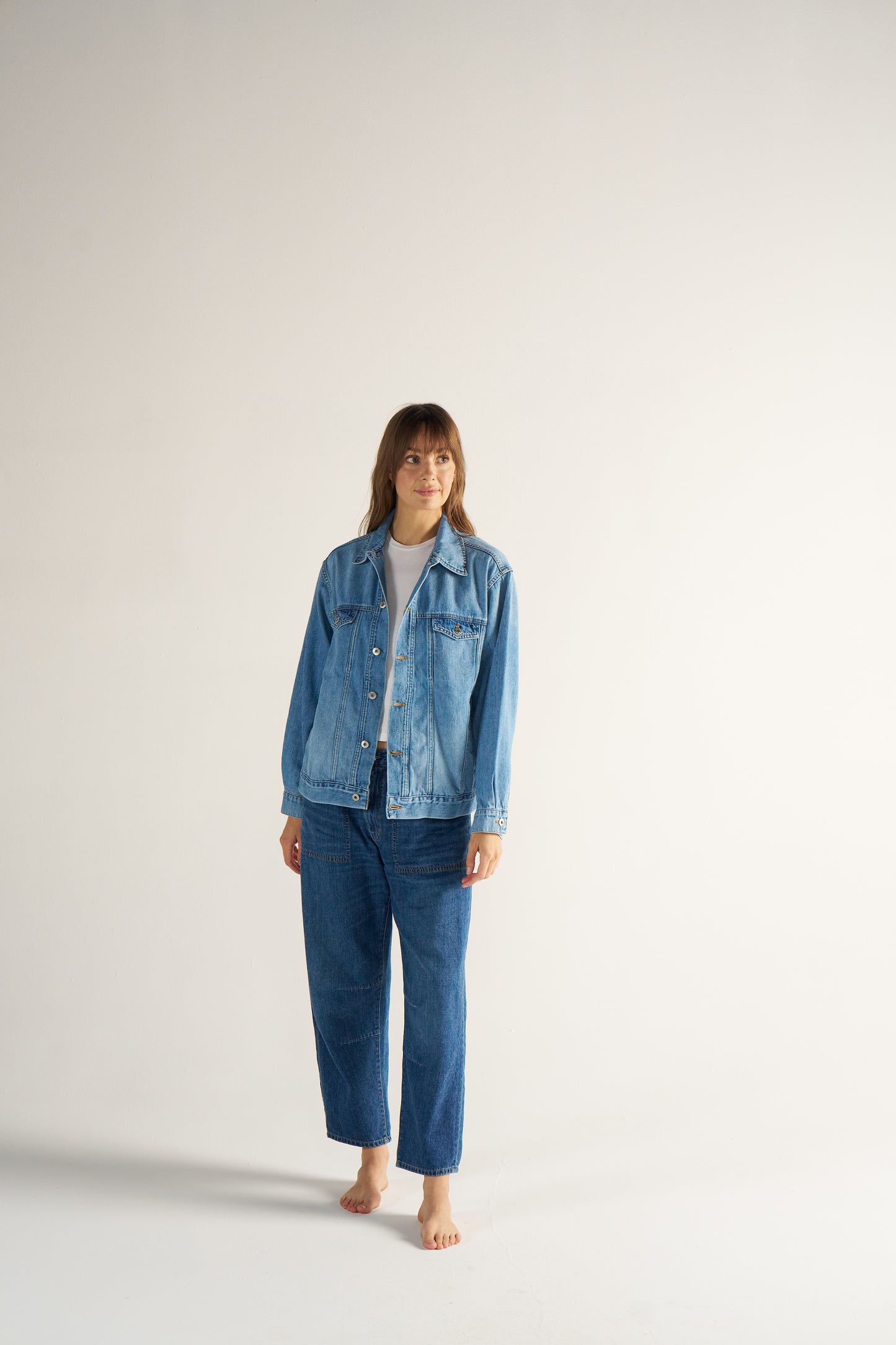 Woman wearing a blue denim jacket and pants on a white background