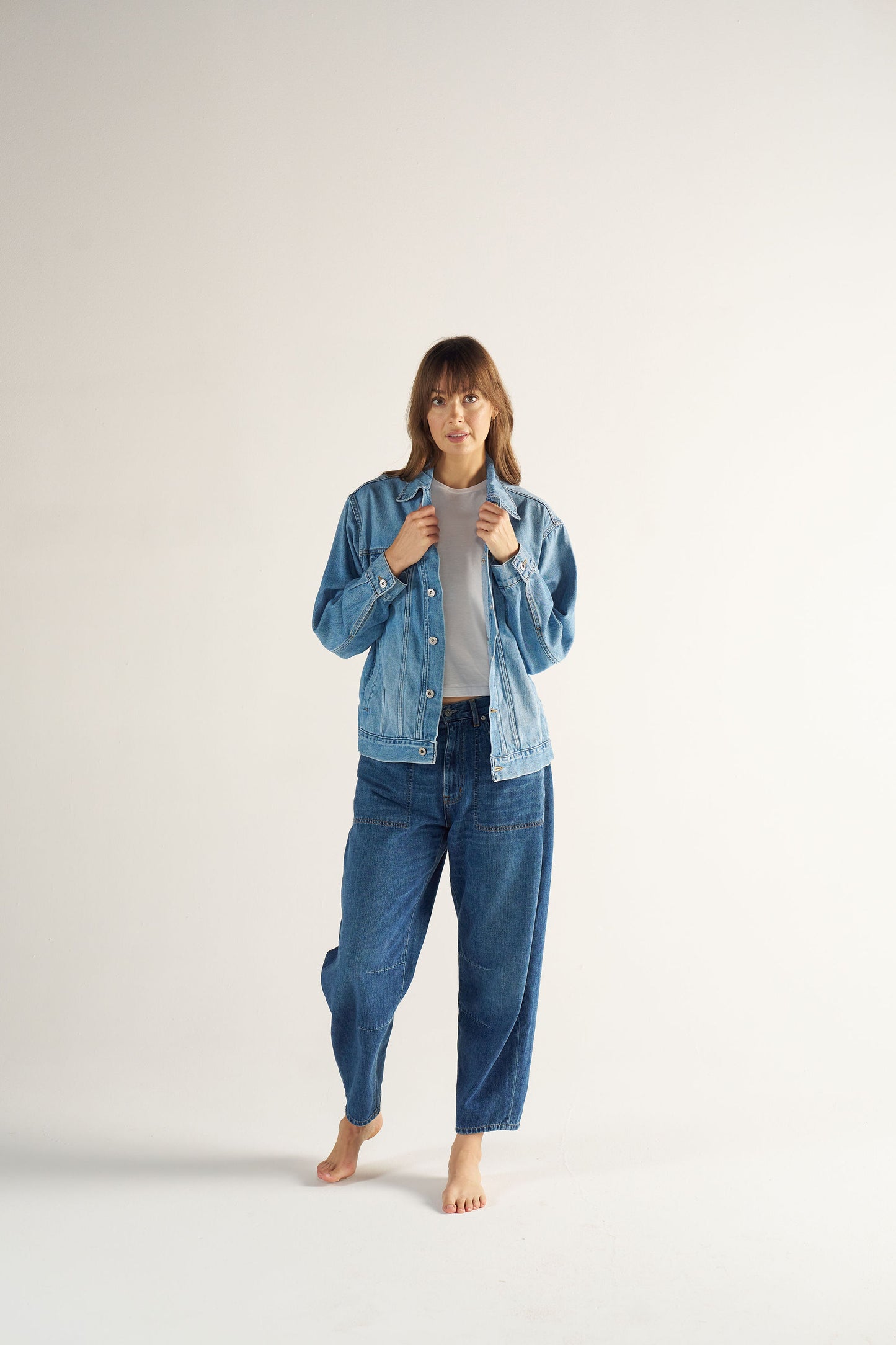 Woman wearing a denim jacket and jeans on a white background