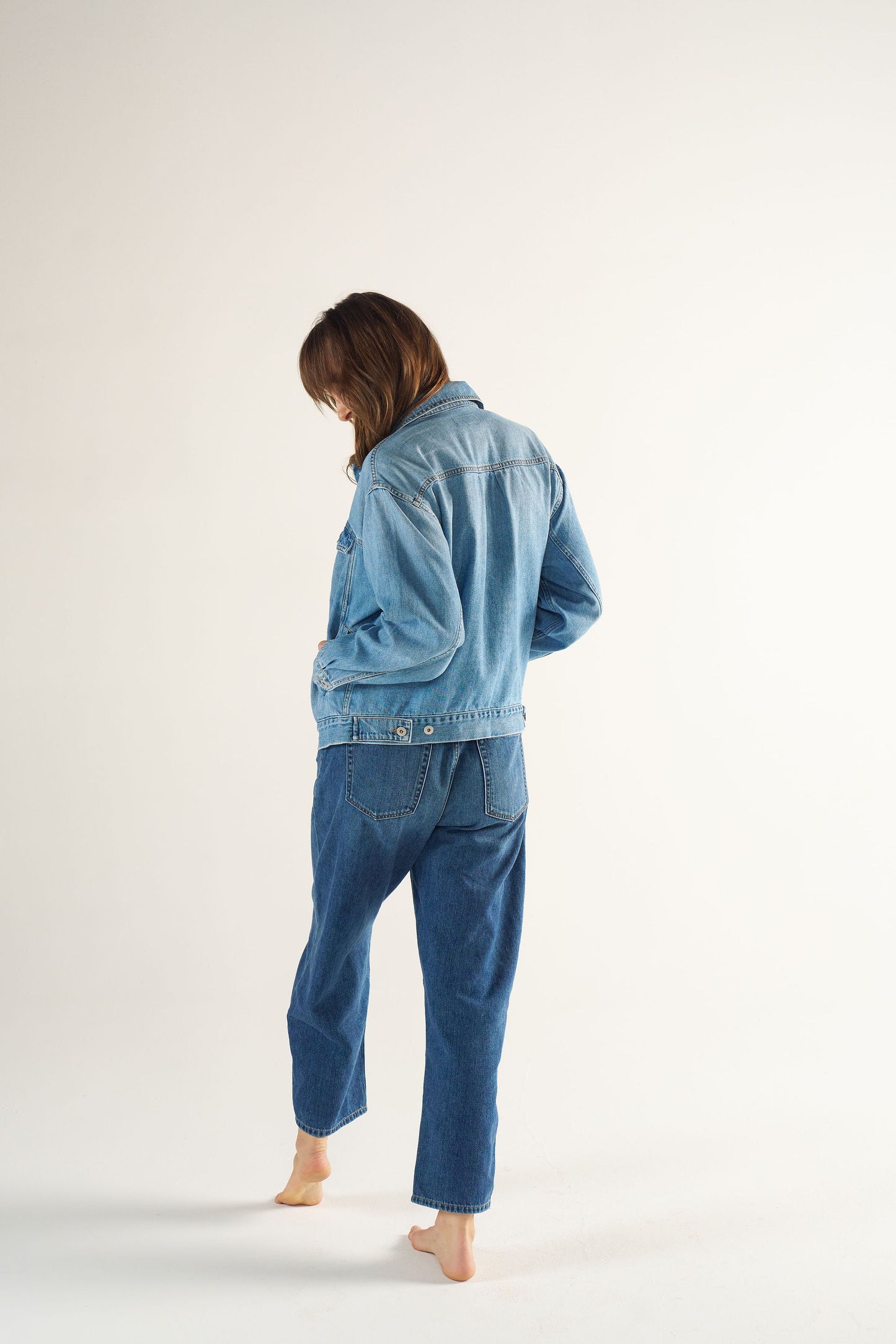 Woman wearing a denim jacket and pants on a white background