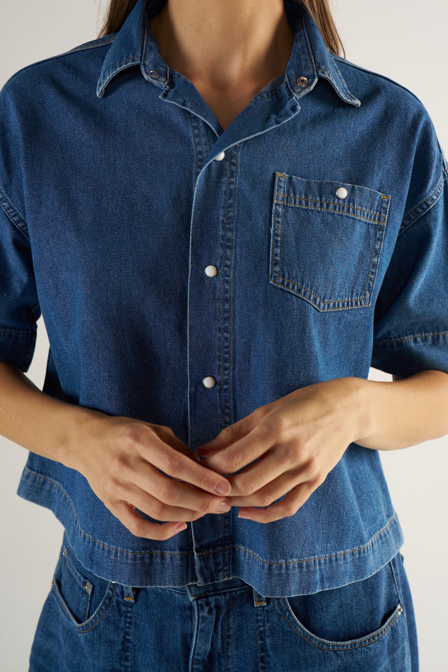 Woman wearing a blue denim shirt with a neutral background