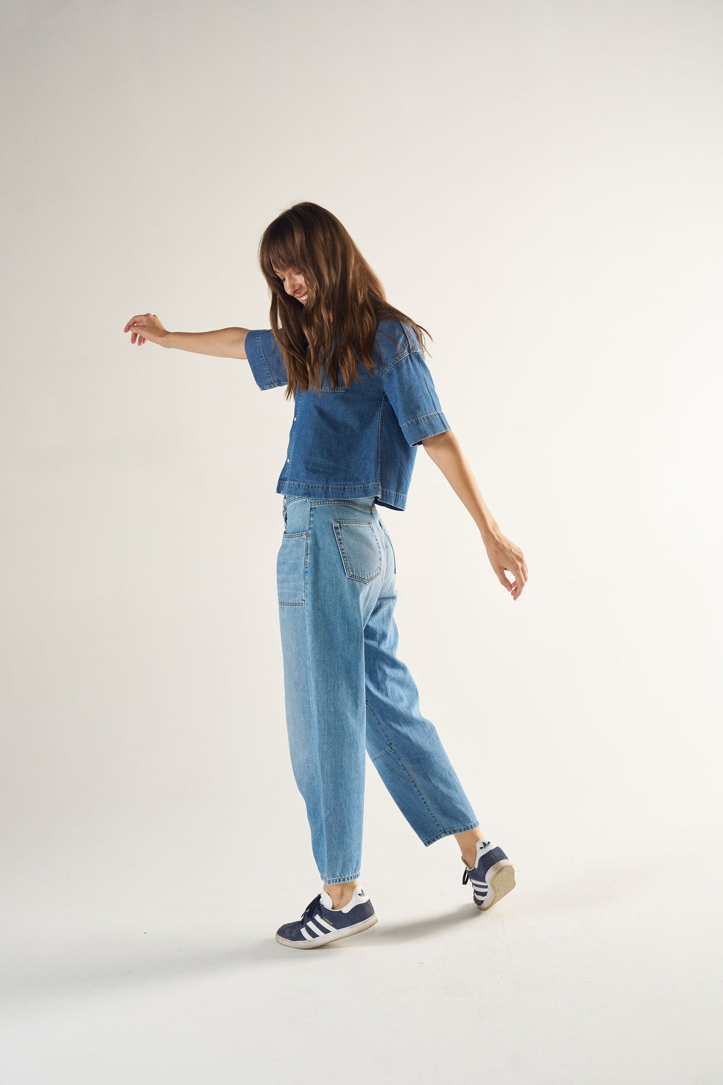 Woman wearing a blue denim outfit with a white background