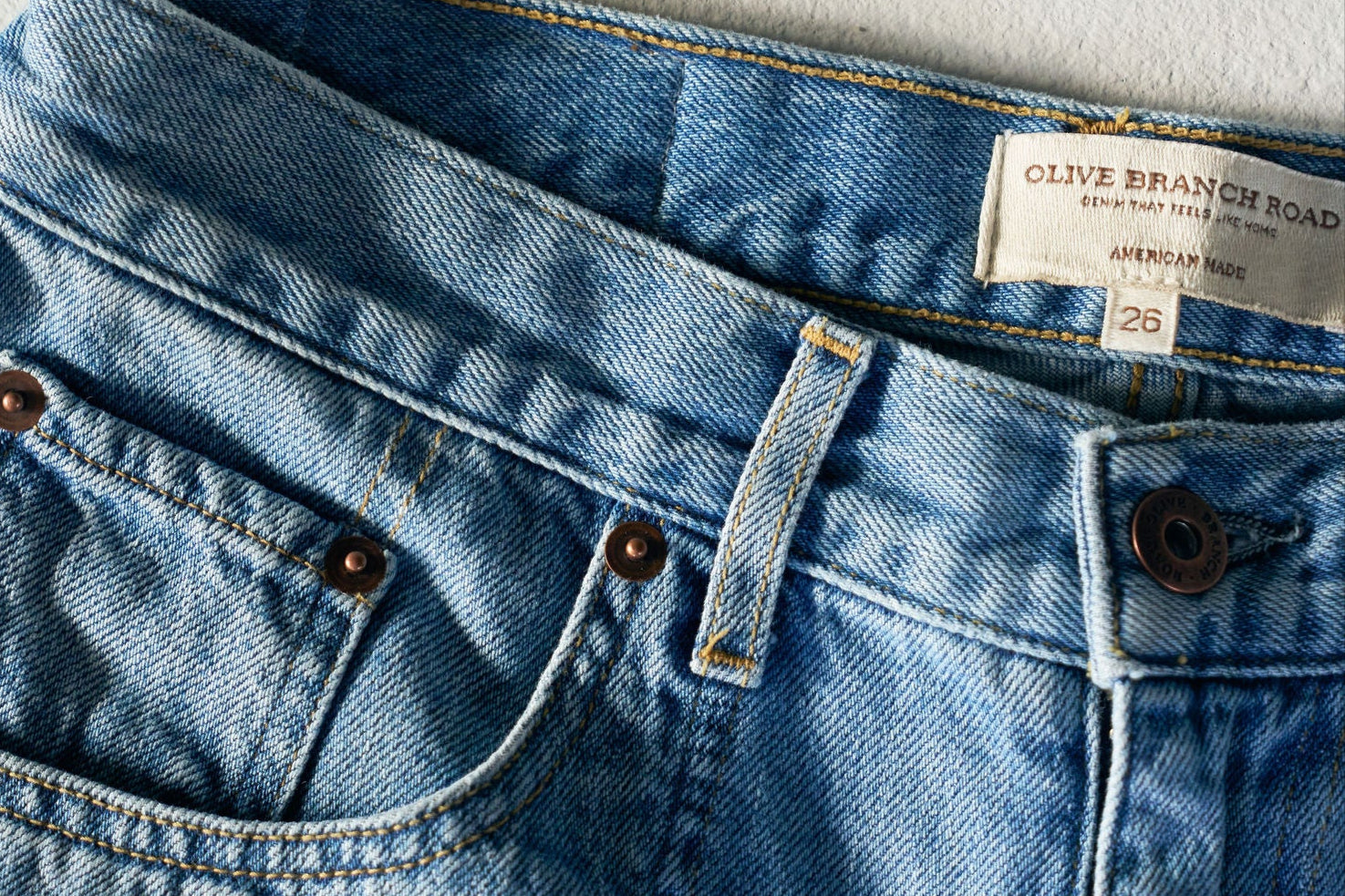 Close-up of blue denim jeans with a brand label on a light gray background