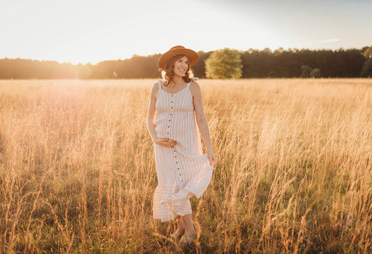 Pregnant woman in a white dress in a field