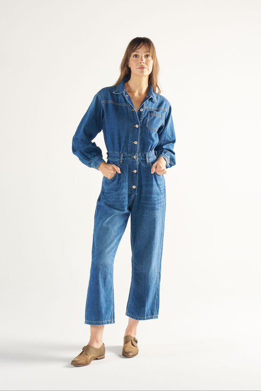 Woman wearing a blue denim jumpsuit on a white background