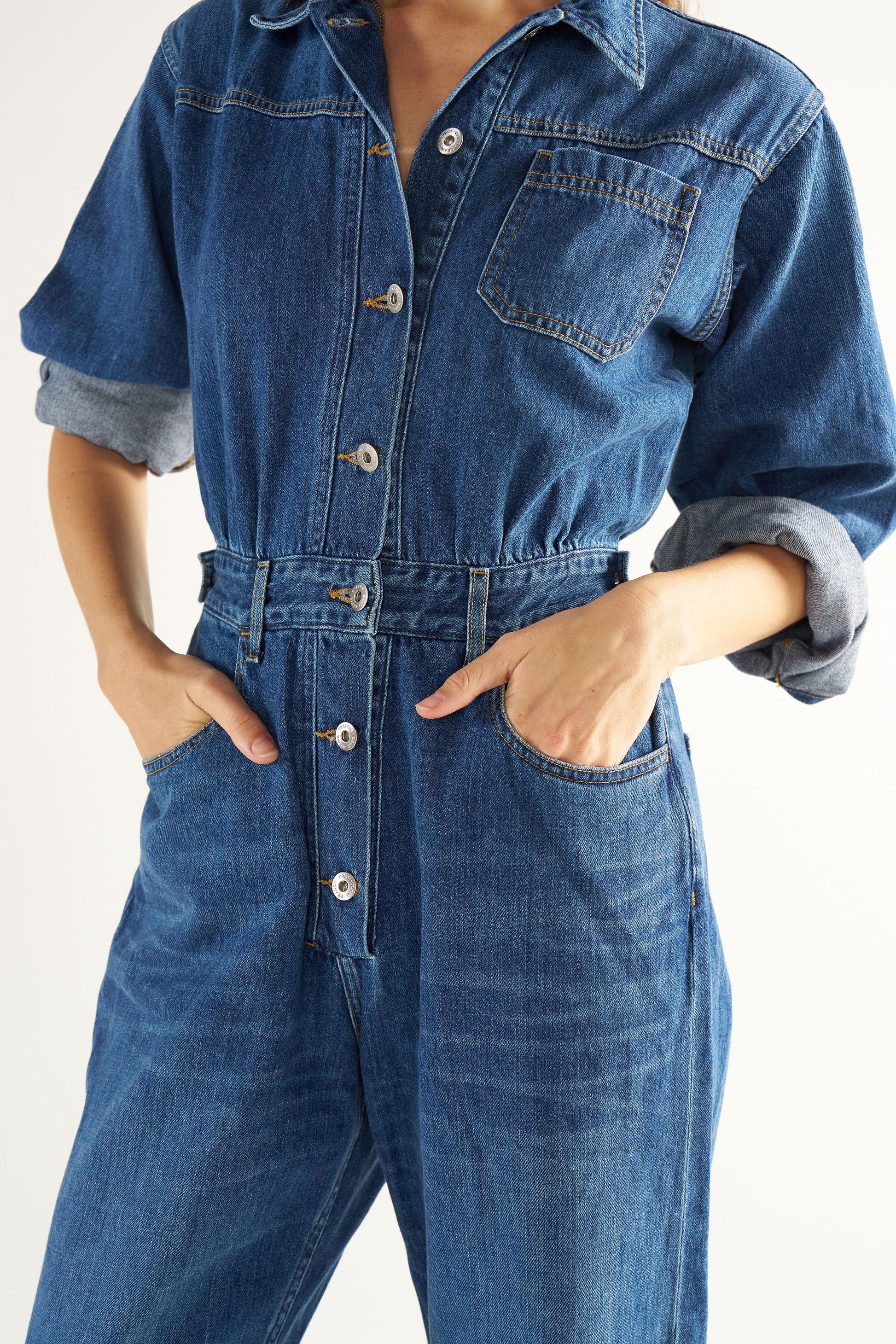 Woman wearing a blue denim jumpsuit on a white background