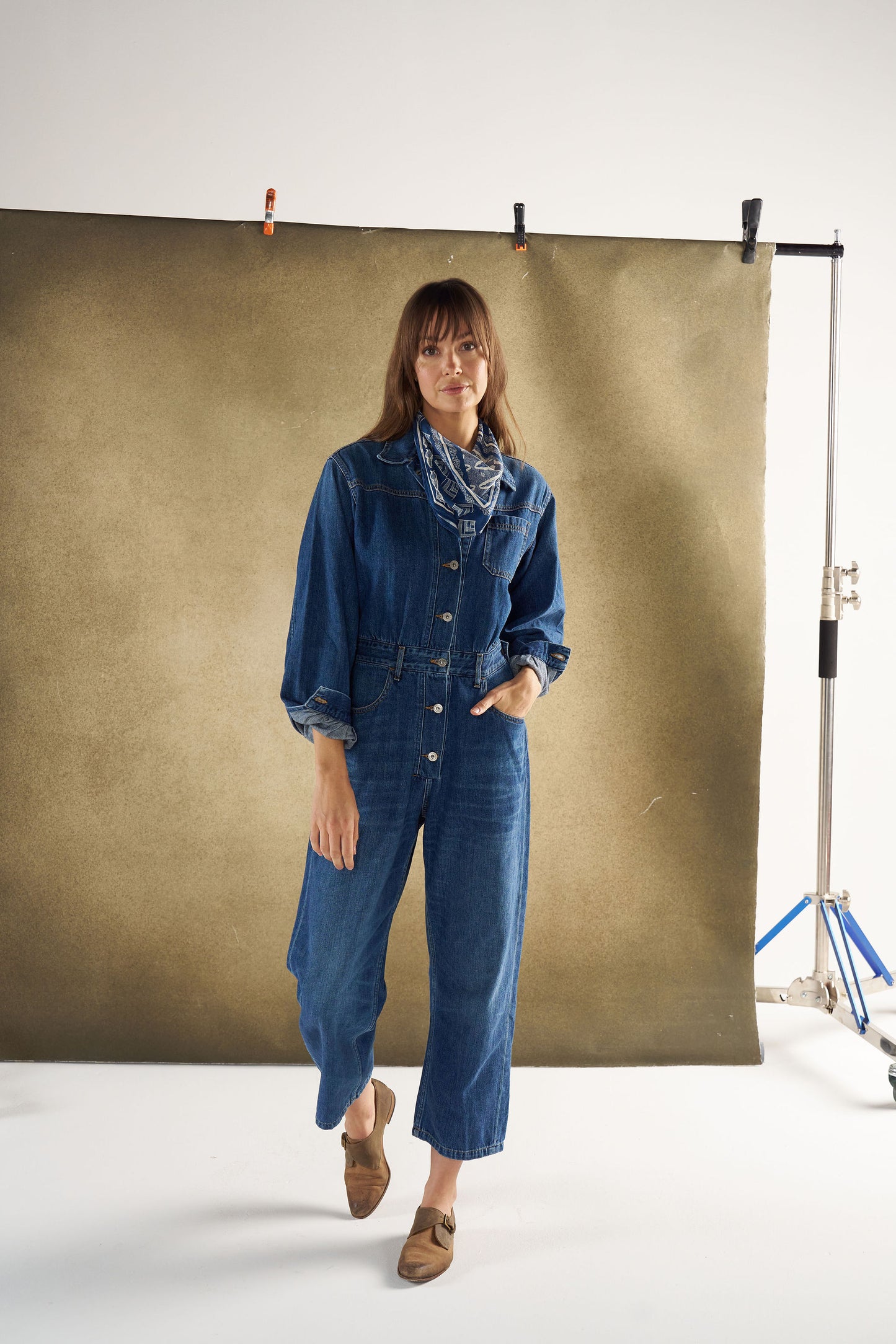 Woman wearing a denim jumpsuit standing in front of a green screen