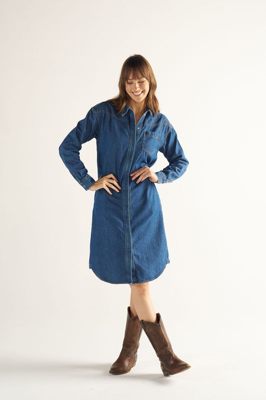 Woman wearing a blue denim dress with brown boots on a white background