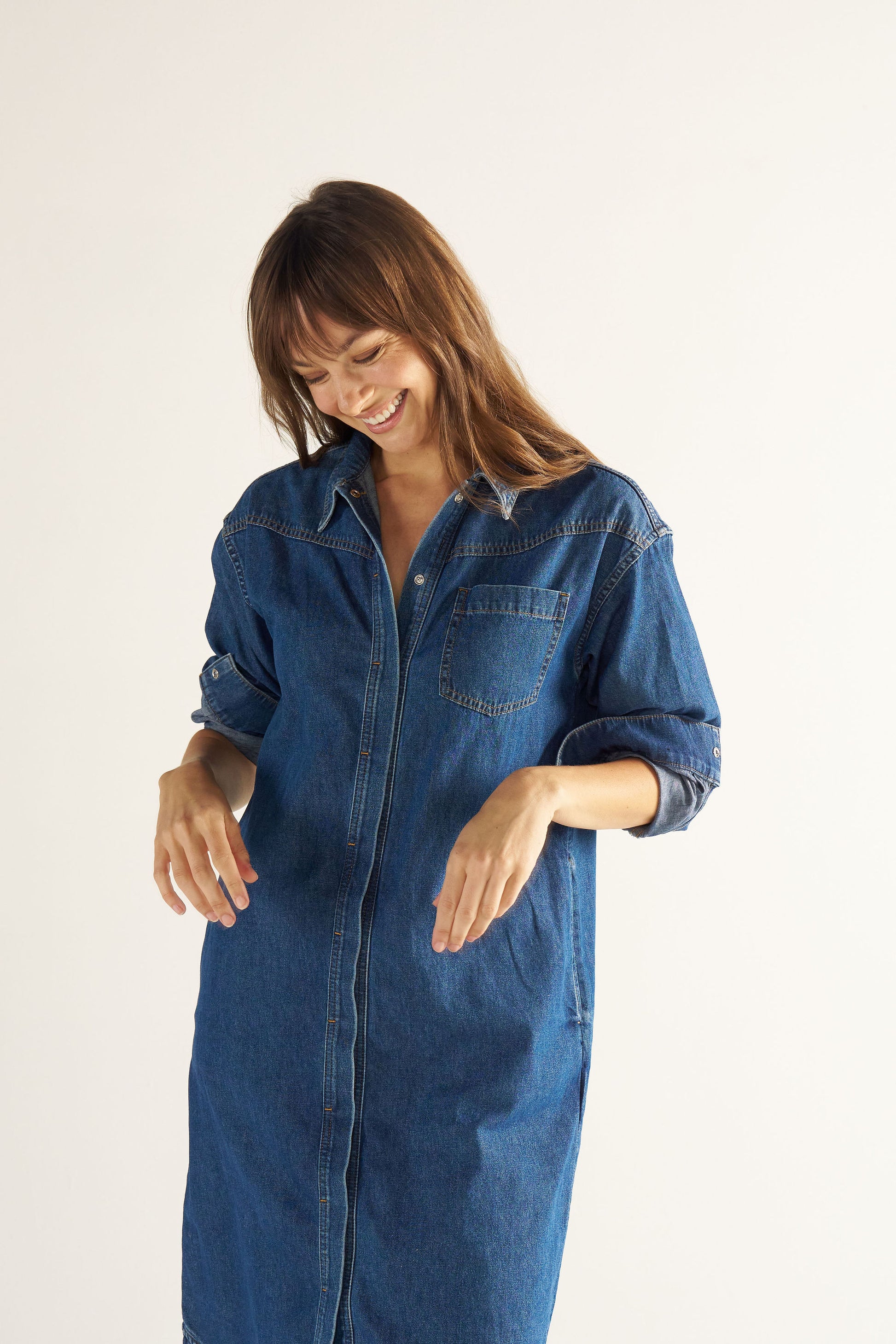 Woman wearing a blue denim dress against a white background