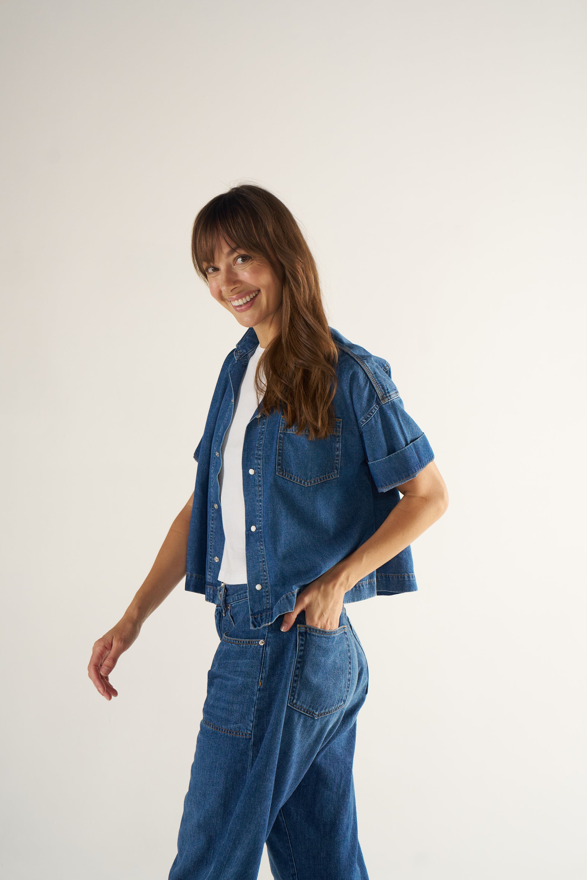 Woman wearing a denim outfit on a plain background