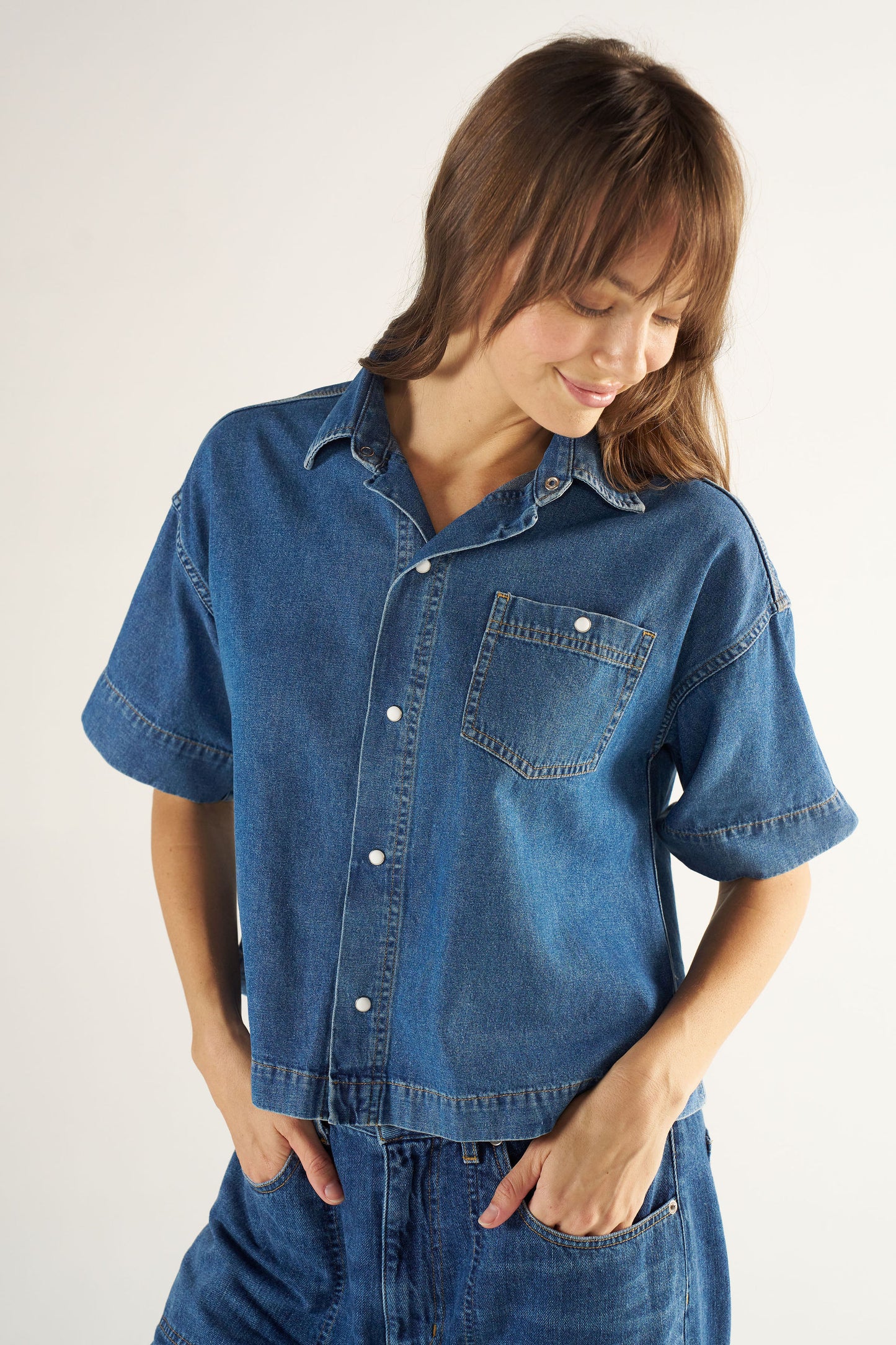 Woman wearing a blue denim shirt and pants on a white background