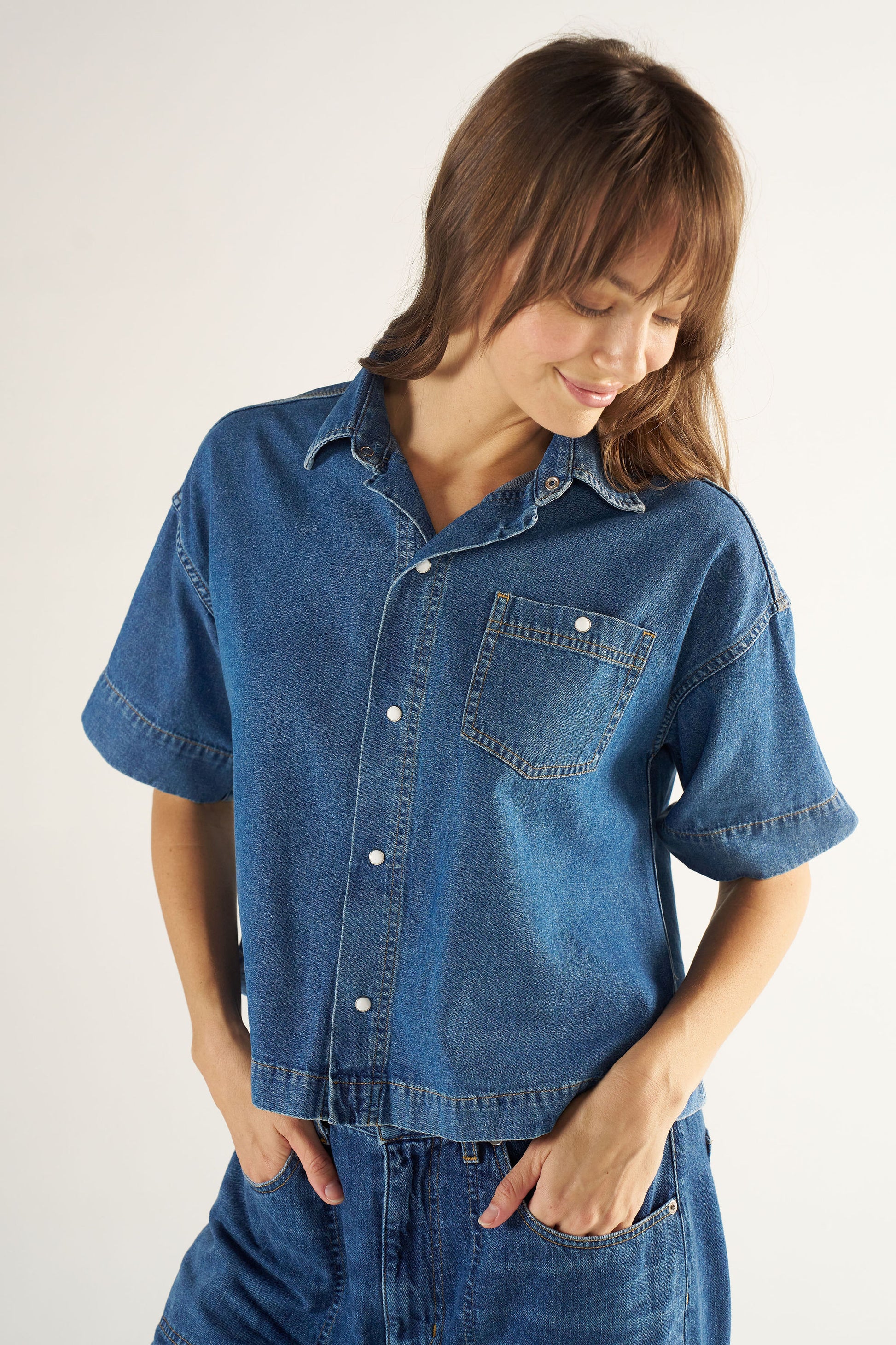 Woman wearing a blue denim shirt and pants on a white background