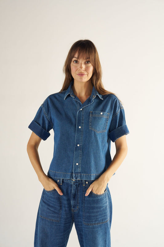 Woman wearing a blue denim outfit on a plain background